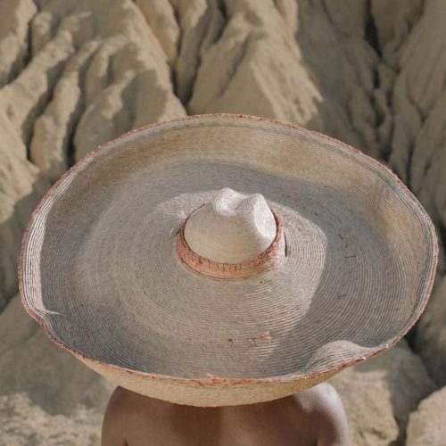 Woman wearing sun hat facing black rock desert